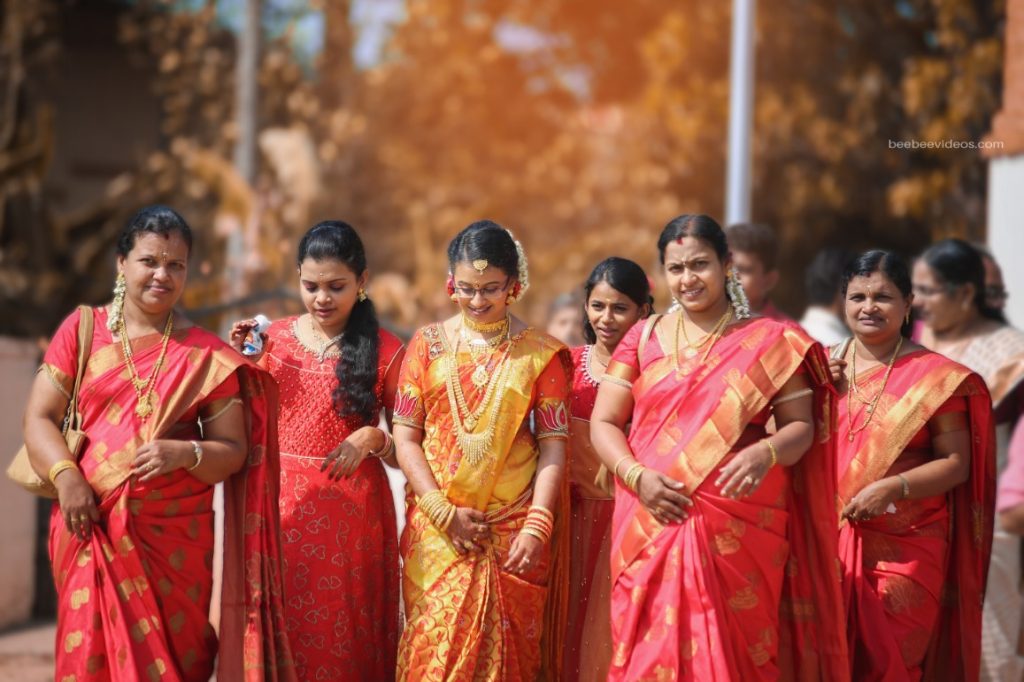 The elegance of weddings, with a bride and her attendants in vibrant sarees, captured by Bee Bee Videos' wedding photography.