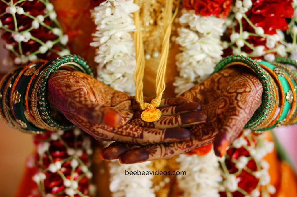 Wedding photography in Coimbatore by Bee Bee Videos, focusing on a bride's adorned hands with rich henna patterns.