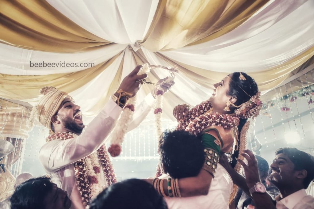 Joyous bride and groom during wedding garland exchange in Coimbatore, captured by Bee Bee Videos' wedding photography.