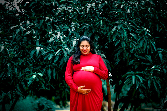 Maternity photo shoot for red wearing woman at Coimbatore Park