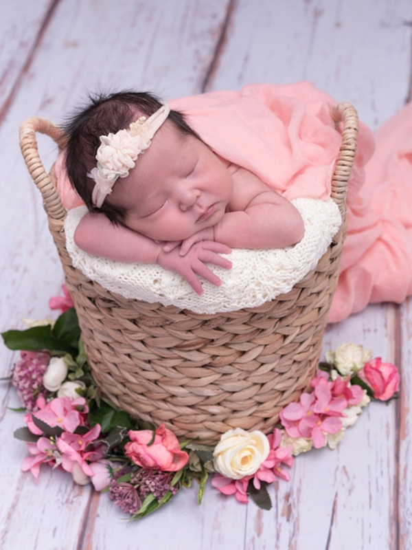 Kids photography captures a tranquil newborn resting in a basket, surrounded by gentle flowers, by Bee Bee Videos.