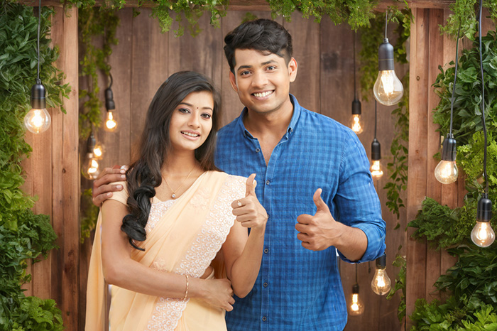 A cheerful couple posing in a live photo booth set up with hanging lights and greenery in Coimbatore, captured by Bee Bee Videos.