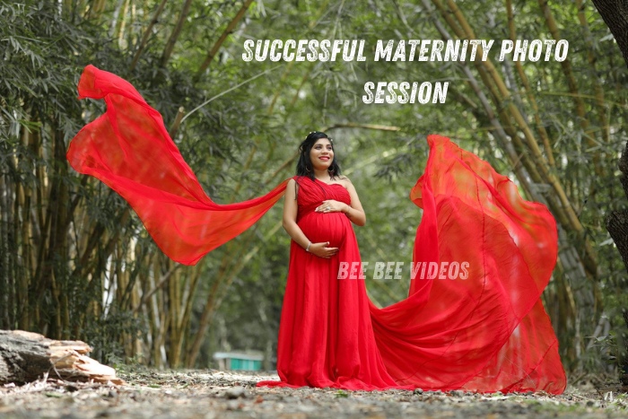 Pregnant woman in a flowing red dress posing in a bamboo forest, capturing a successful maternity photo session, photographed by Bee Bee Videos, top maternity photographers in Coimbatore