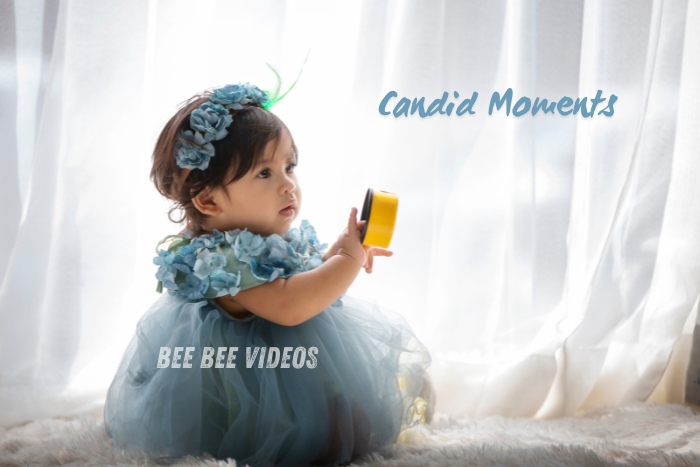 Bee Bee Videos & Photography captures a candid moment of a toddler in a blue dress holding a yellow toy, against a soft, natural light background. Highlighting beautiful candid moments in kids photography in Coimbatore, perfect for preserving childhood memories."