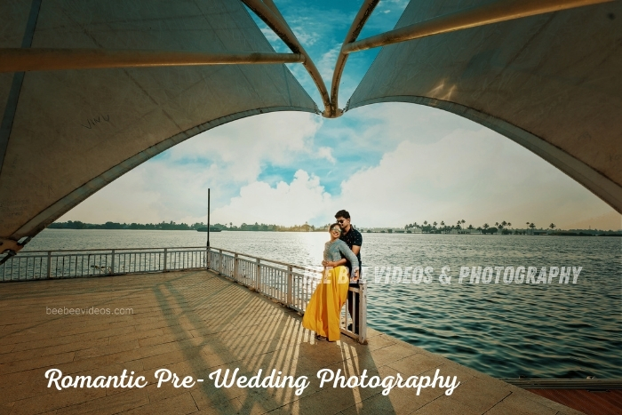 Romantic pre-wedding photoshoot by the lakeside with a couple posing under a unique architectural canopy